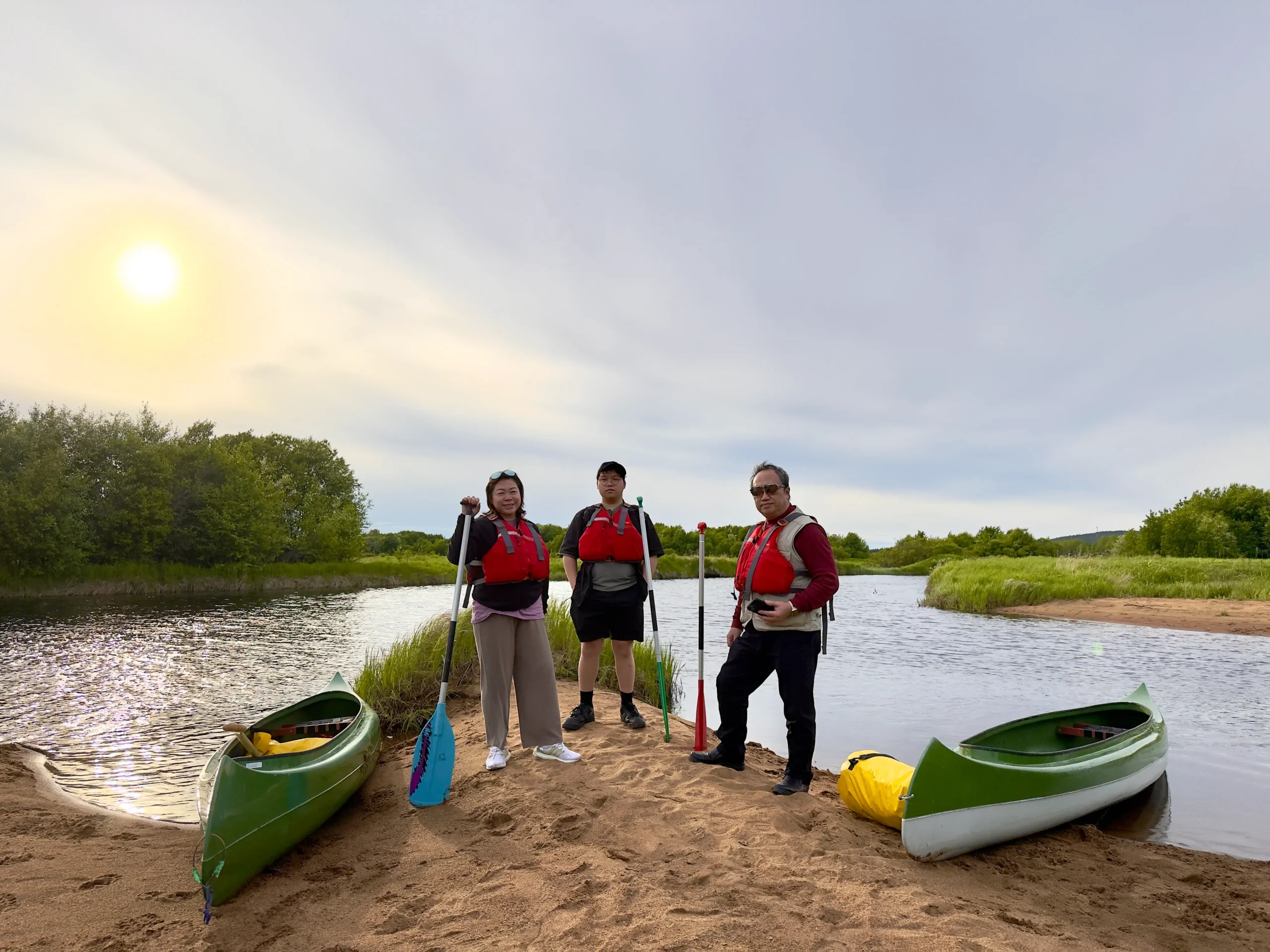 Group with canoes on a river beach in the Lapland summer