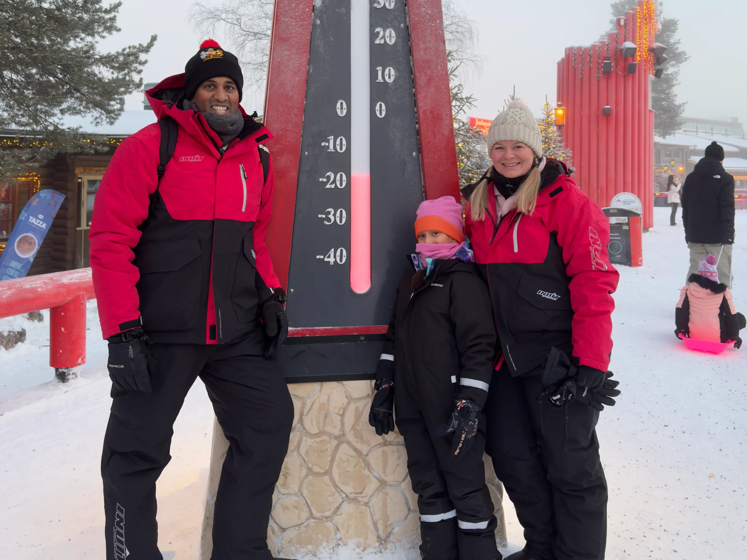 Guests in rented winter clothing beside a giant thermometer in the snow