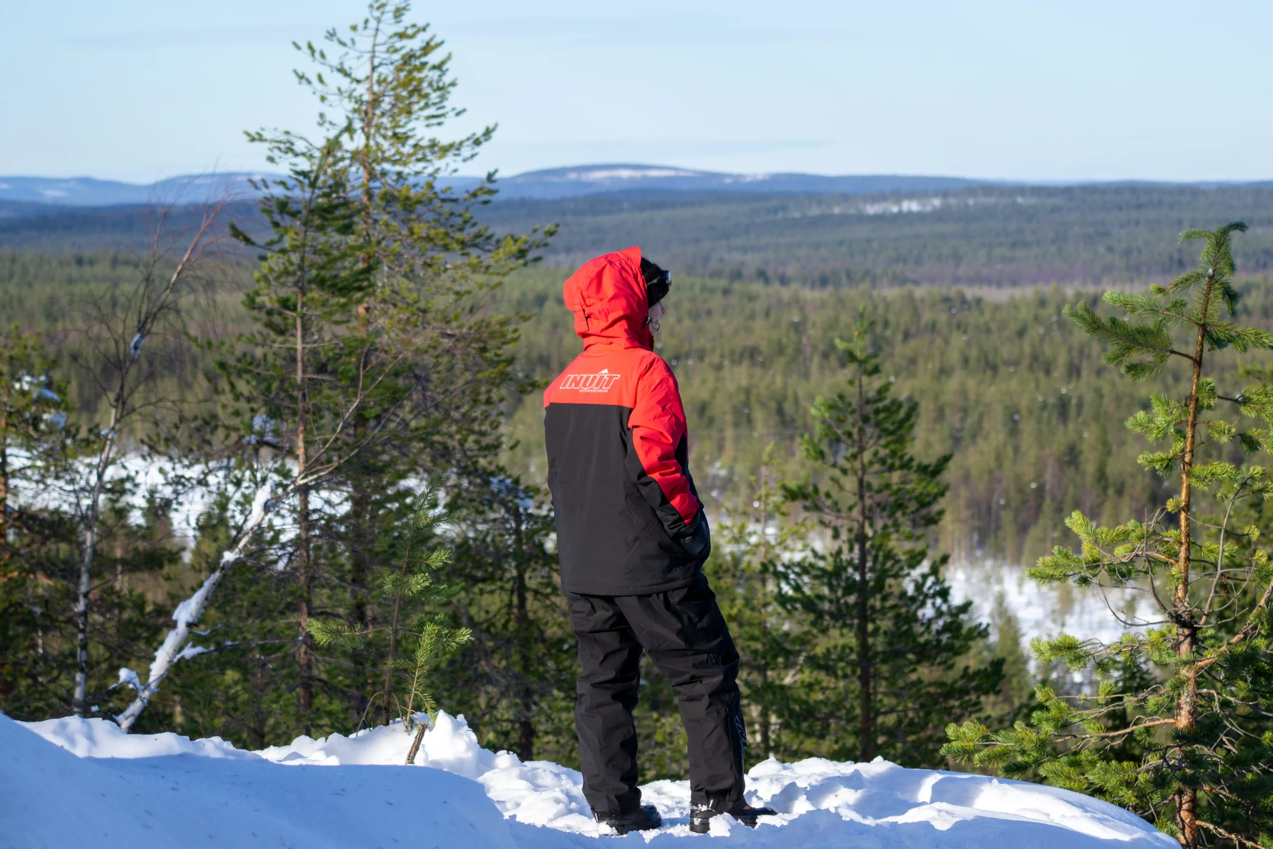 Guest in a red jacket looking out over snow-covered forest